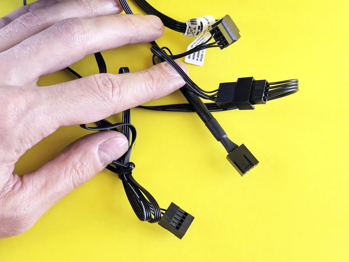 A hand on a set of computer cables and connectors.