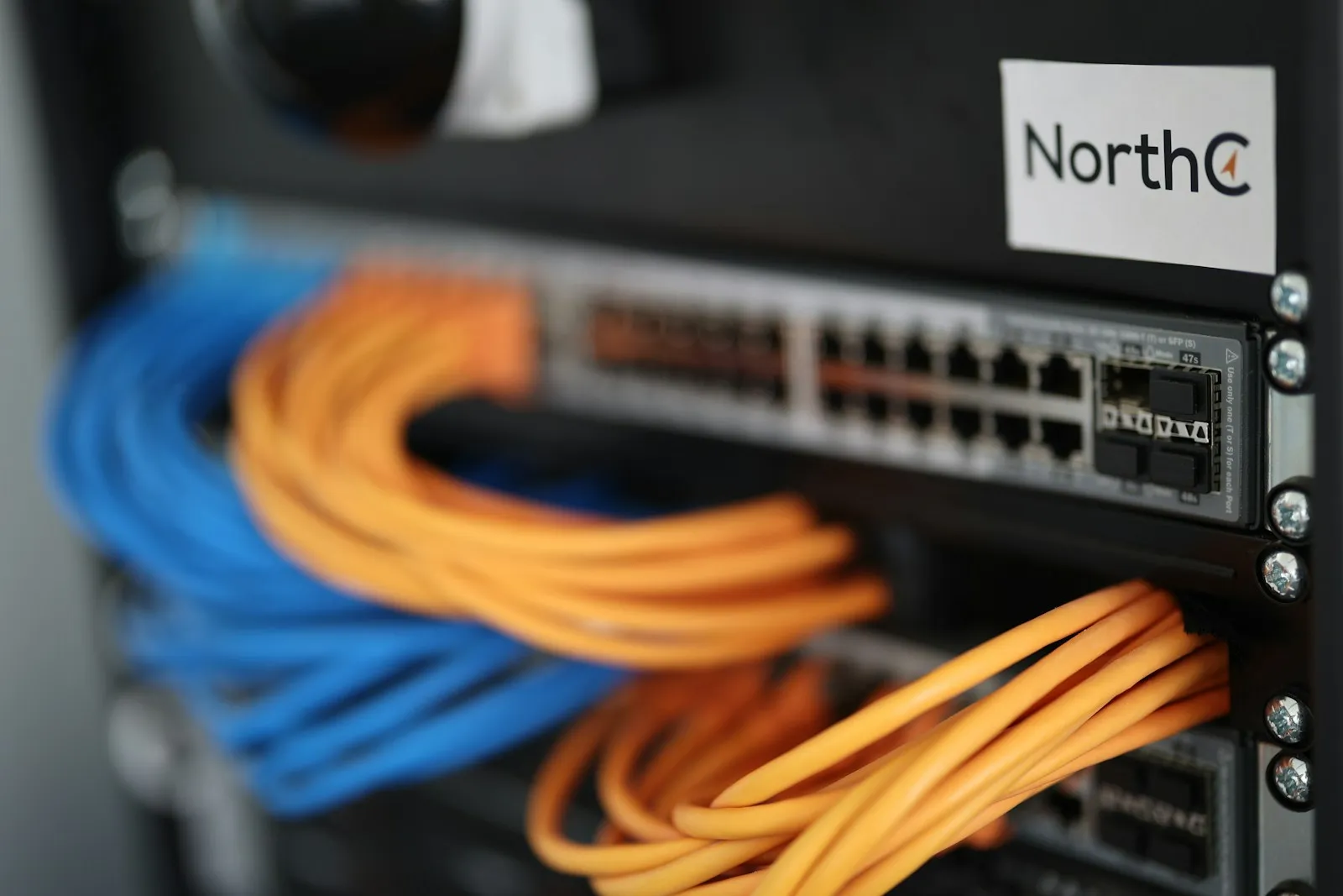 A network switch in a data-center rack, with RJ45 ports, SFP cages, and looped patch cables.