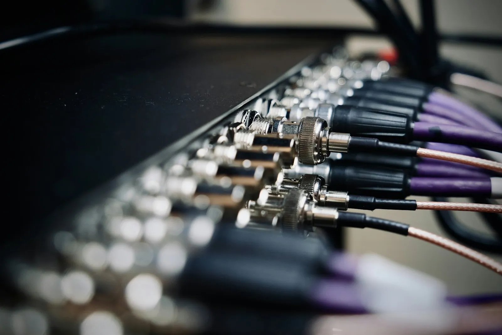 A row of BNC-terminated coaxial cables plugged into the back of a video distribution panel.
