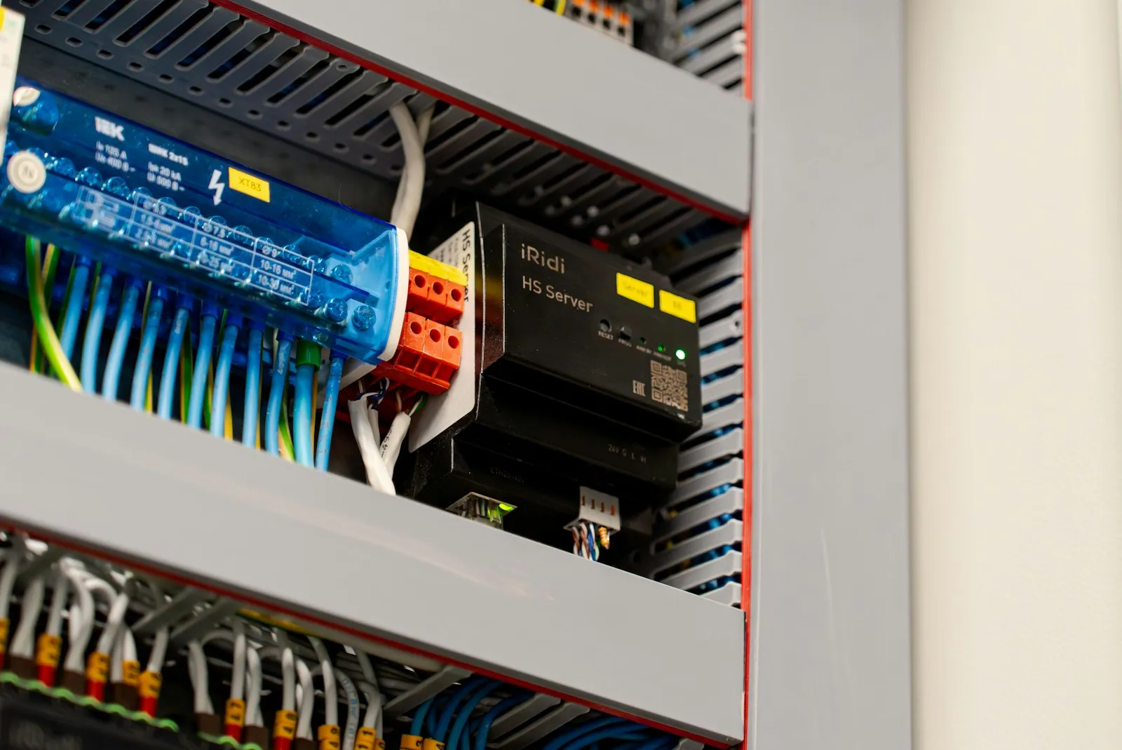 A control cabinet with DIN-rail terminal blocks, a distribution block, wire ducts, and a 24V DIN-rail controller.