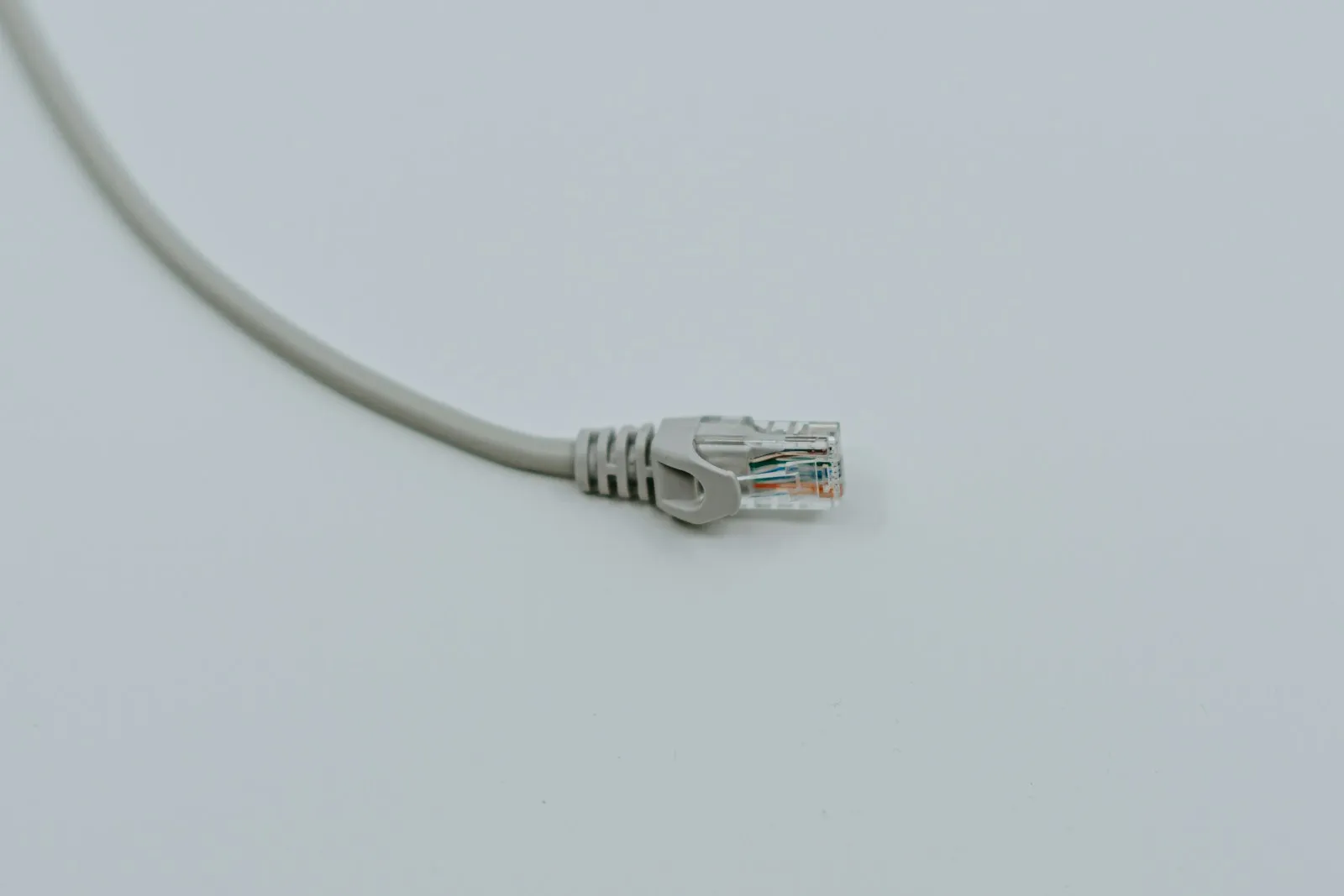 A gray RJ45 Ethernet plug with the eight twisted-pair conductors visible through the clear housing.
