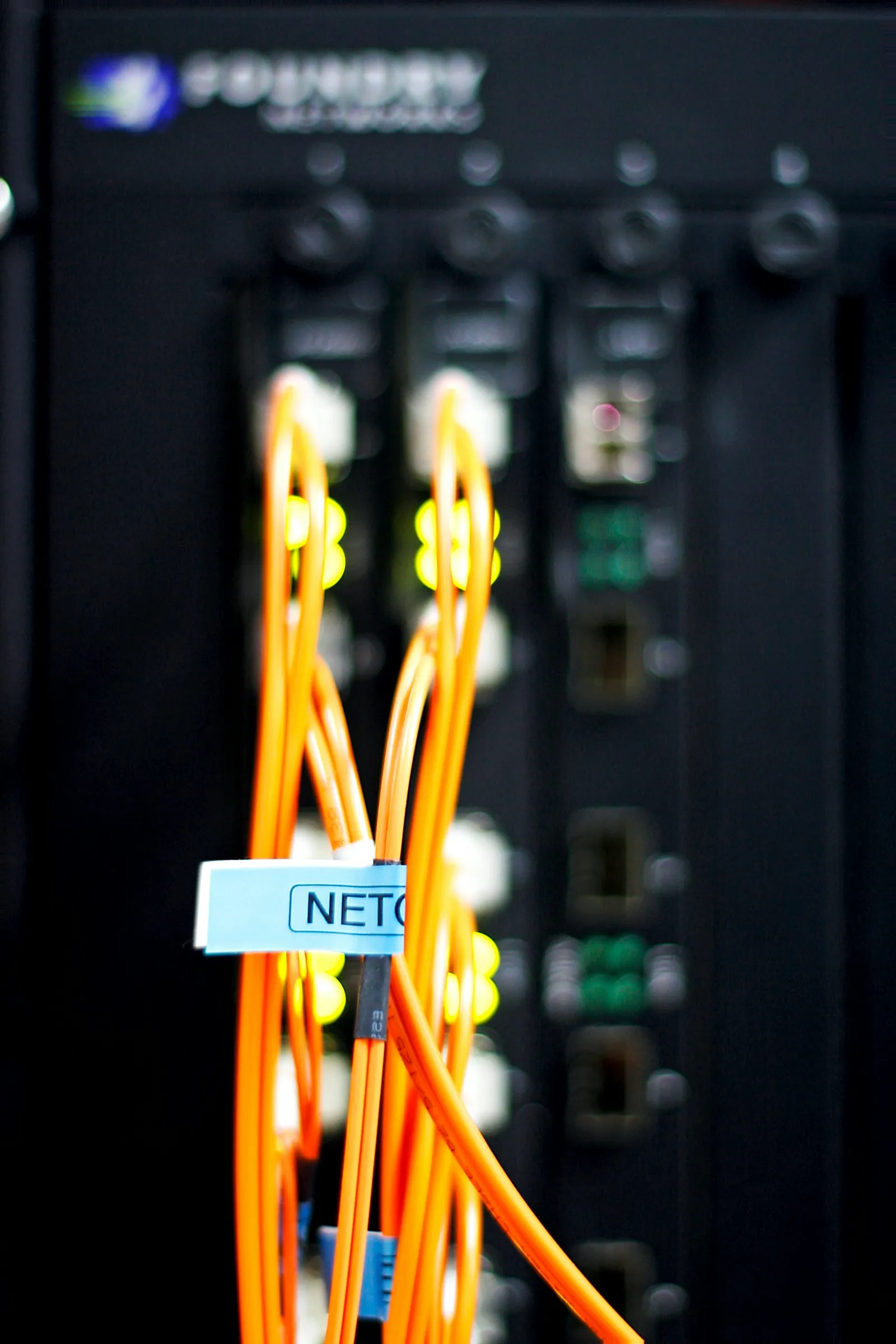 Orange multi-mode fiber jumpers looped into the front of a network switch.