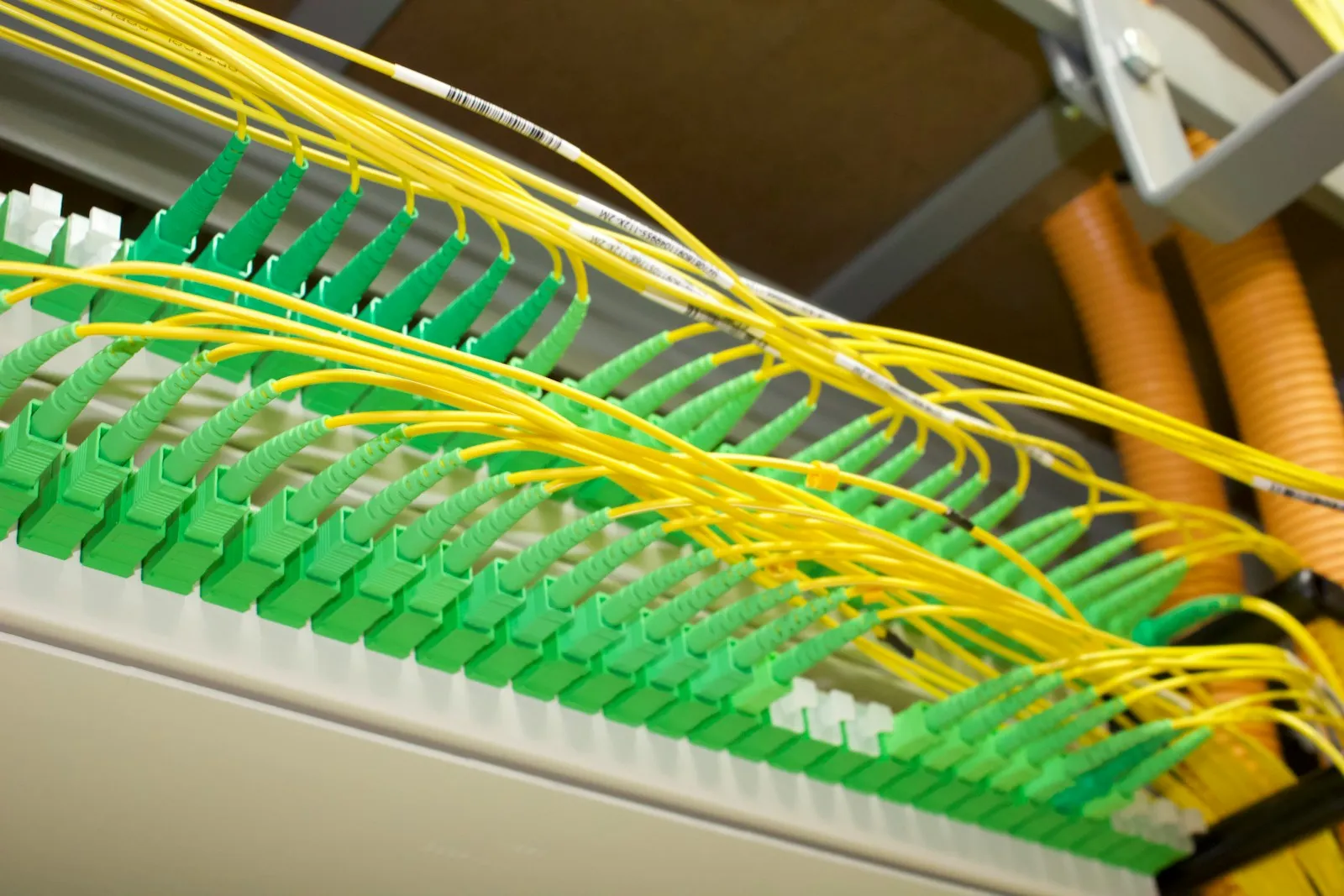 Yellow single-mode fiber patch cords terminated in green SC/APC connectors across a fiber distribution panel.