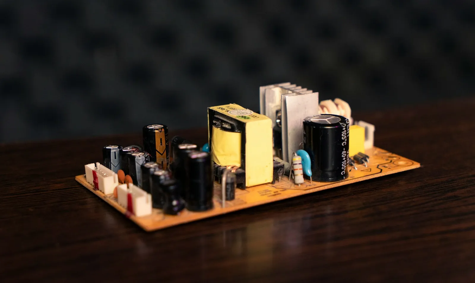 An open-frame switching power supply board showing the transformer, heatsink, and electrolytic capacitors.