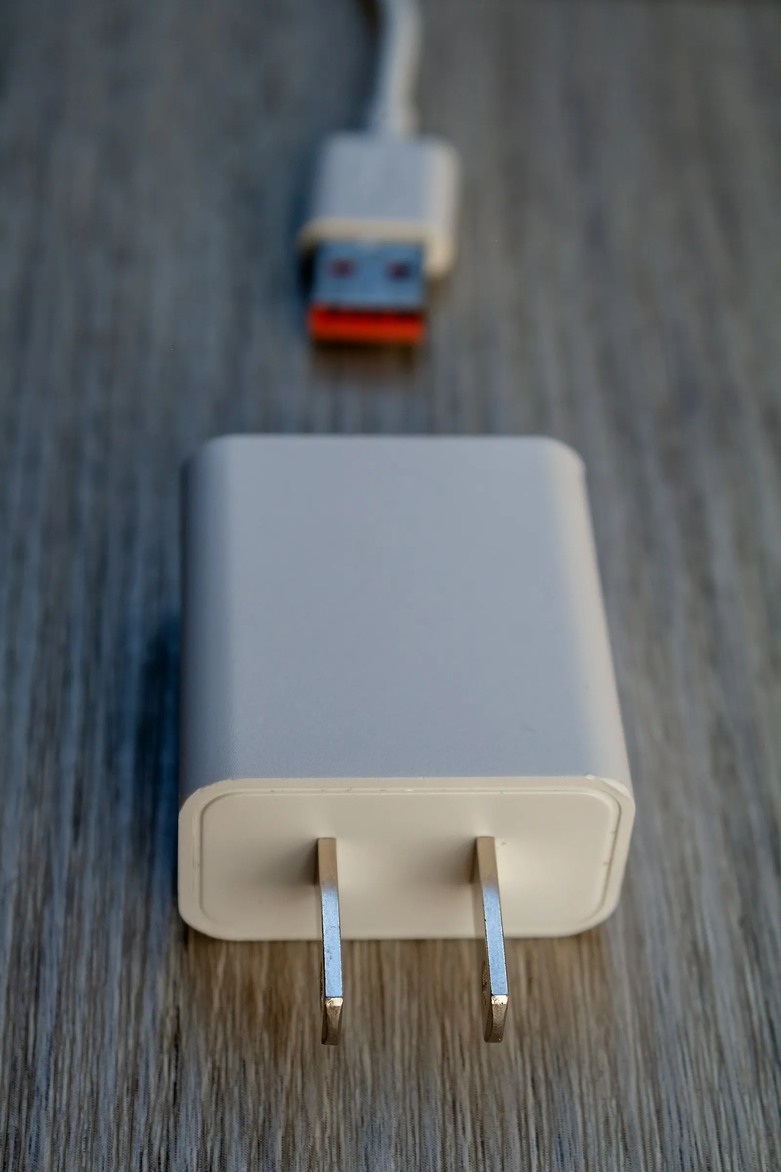 An unbranded white wall-mount power adapter with a US plug and its output cable.