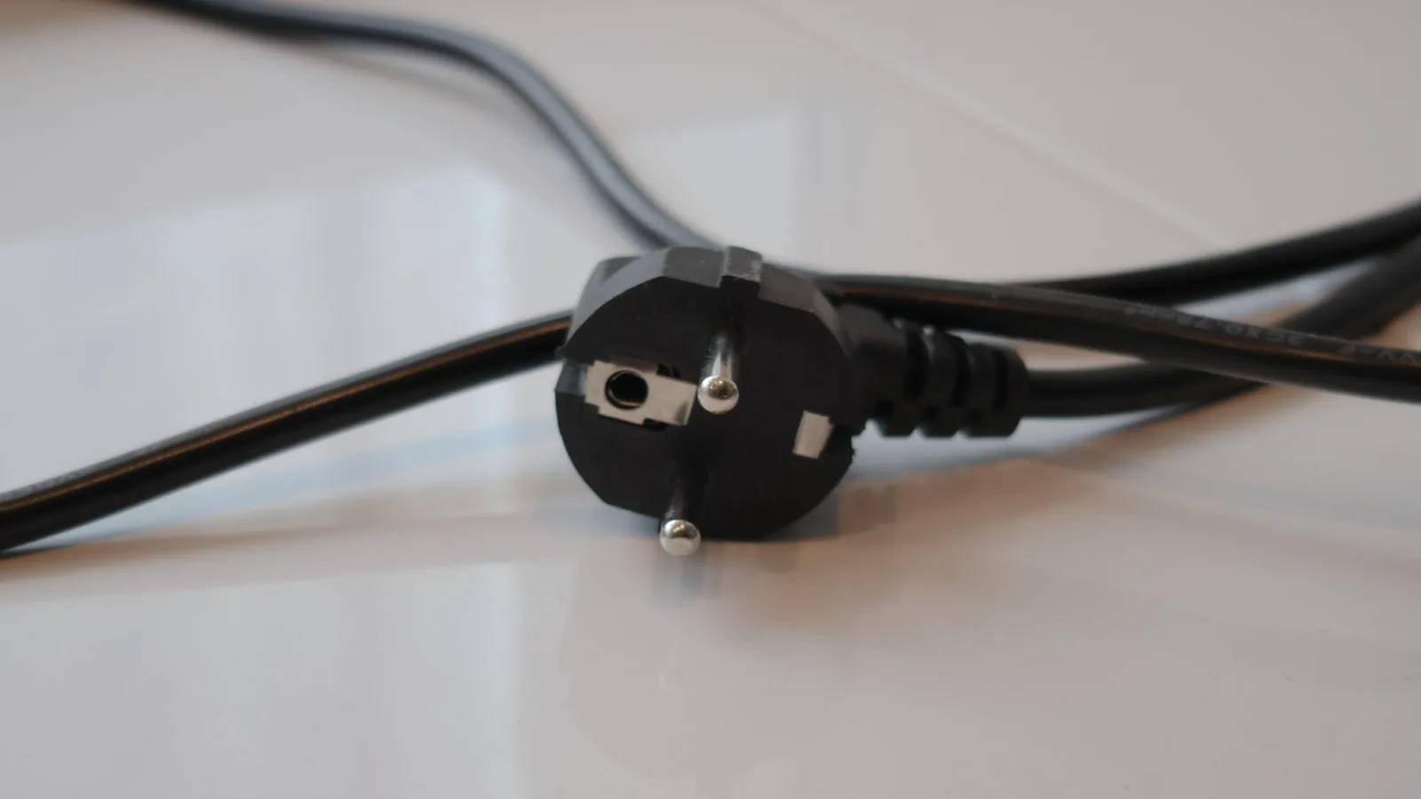 A molded power cord plug with the cordage type and gauge printed along the black jacket.