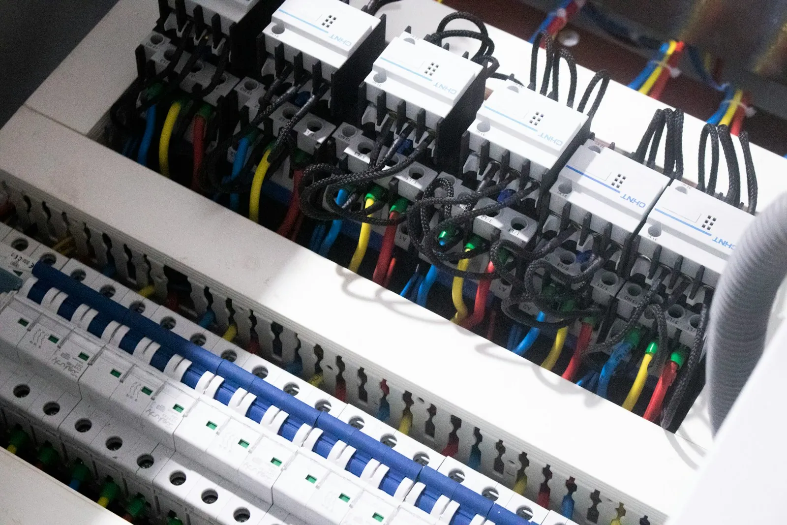 A control cabinet with rows of DIN-rail breakers, contactors, and colored wiring.
