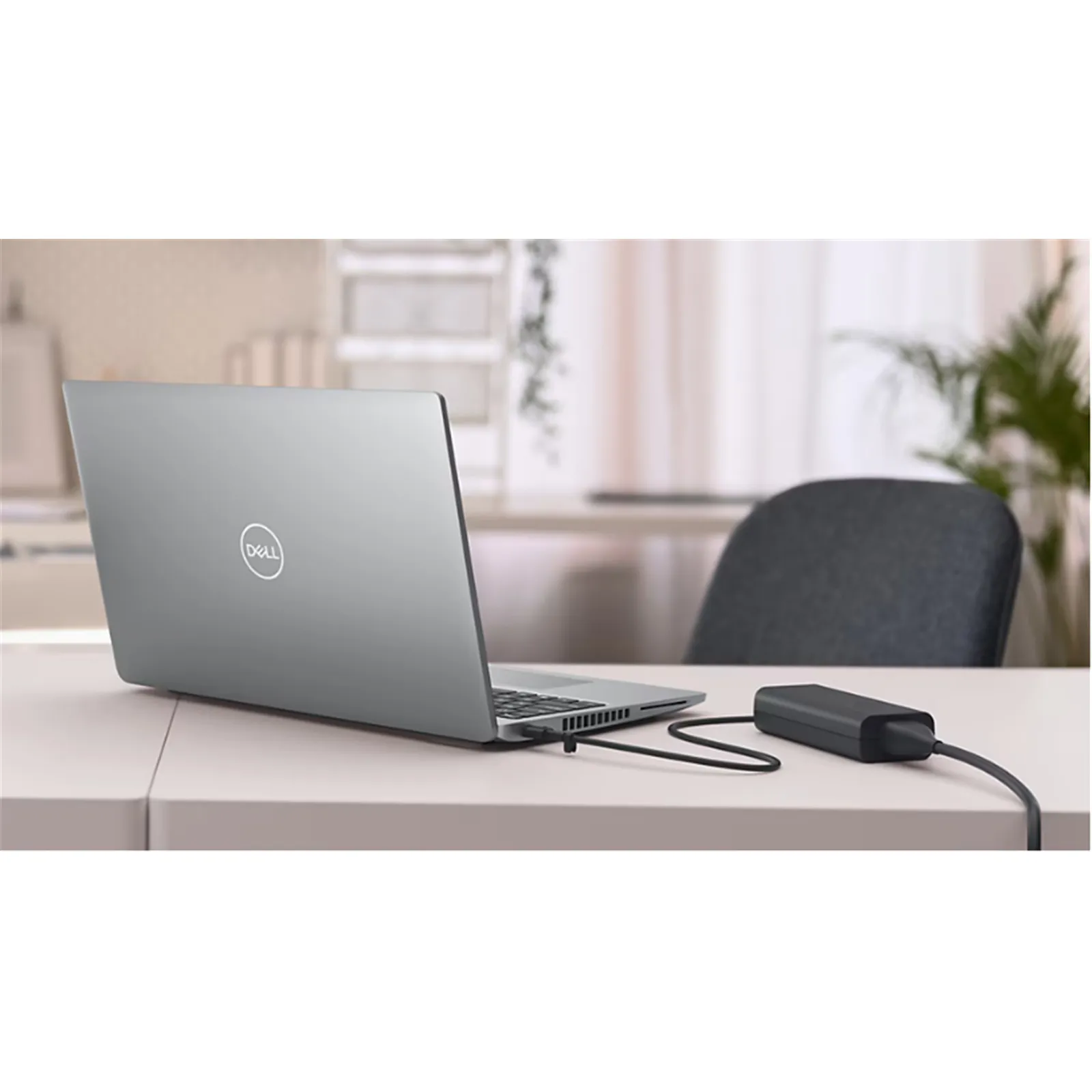 A laptop on an office desk powered by an external AC/DC power adapter and cord.