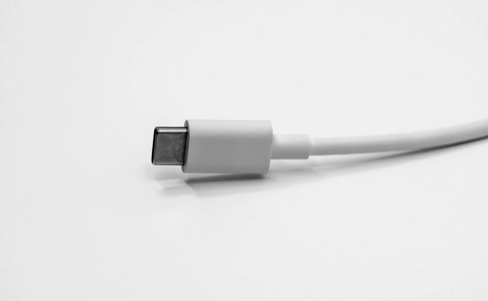 A white USB-C cable plug photographed close up against a white surface.